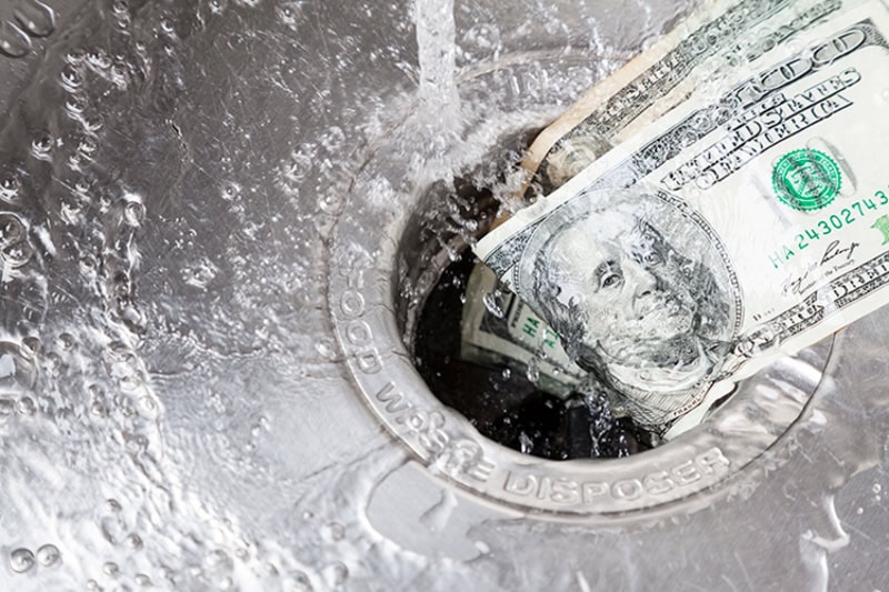 Money being washed down a drain.