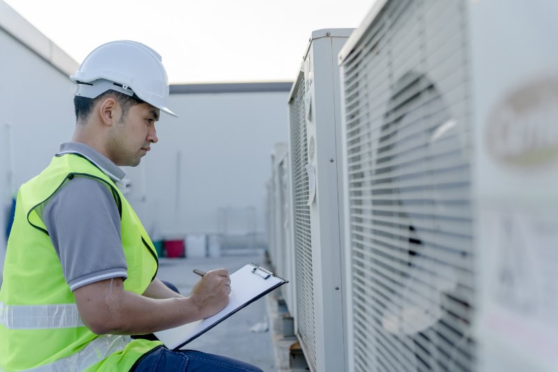Asian maintenance engineer recheck works on the roof of factory. contractor  inspect compressor system and plans installation of air condition systems in construction site of modern buildings.