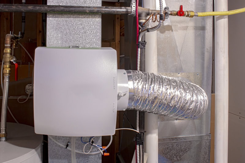 A home humidifier attached to the return duct with a bypass connection to the supply hot air duct.